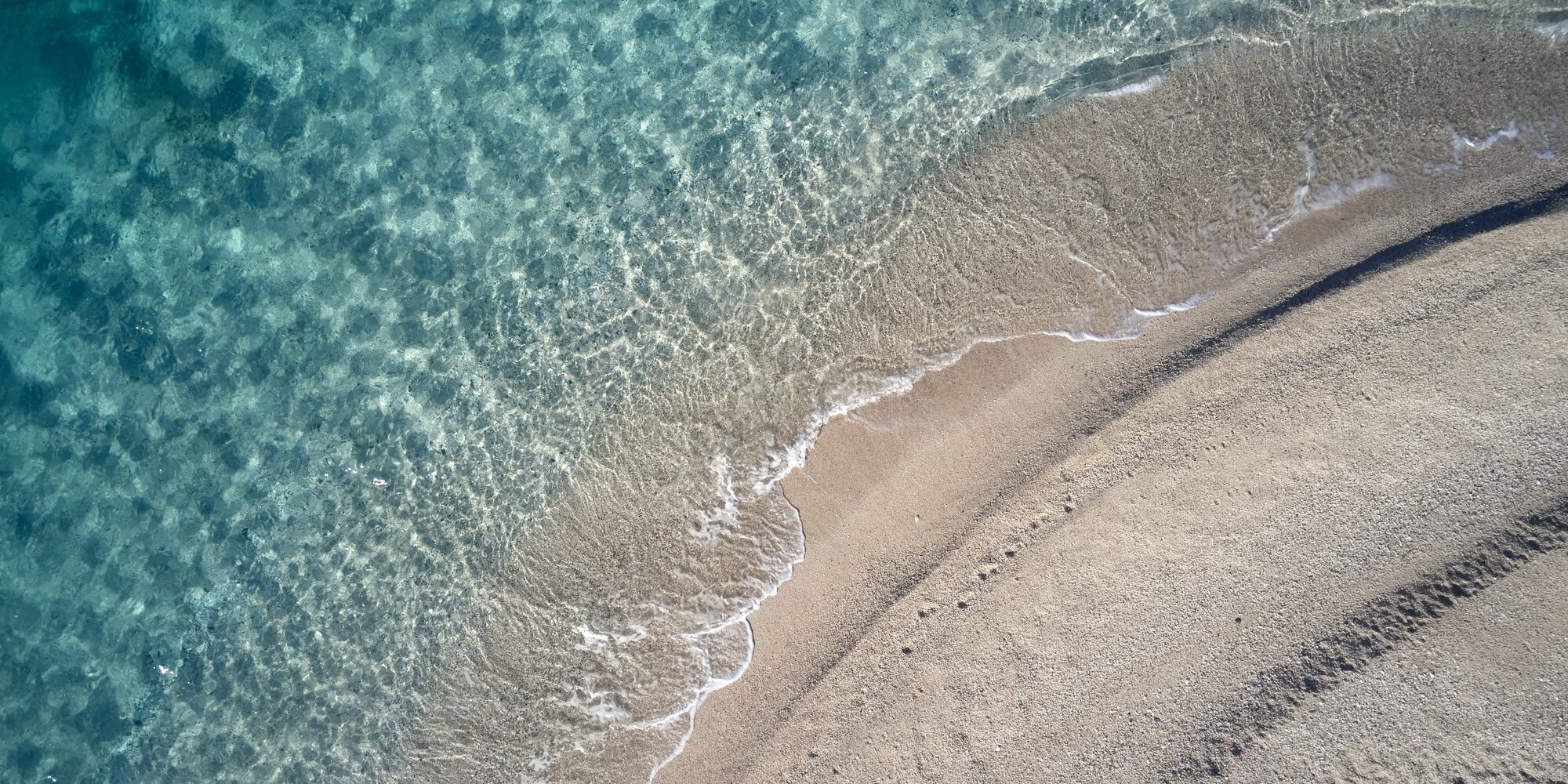 Top view of beach and coastline with clear water.